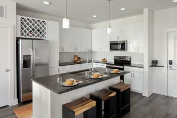 A kitchen with white cabinetry and a large island with a black countertop